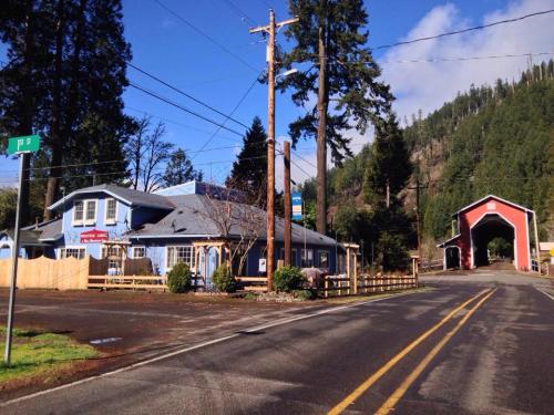 A blue building with a sign, surrounded by trees, near a red covered bridge on a quiet road.