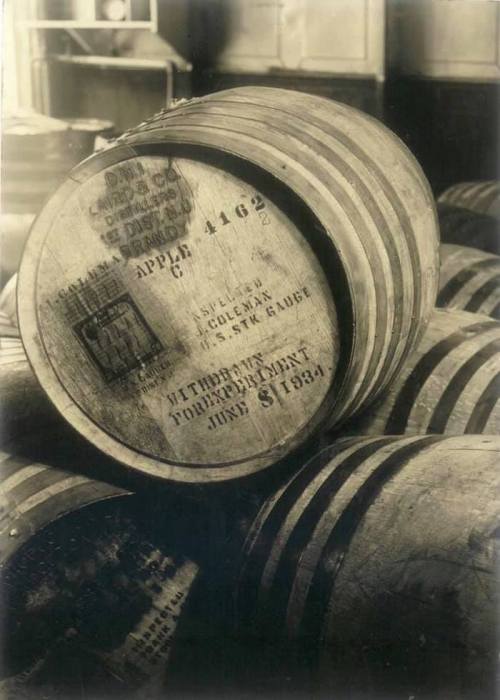 A stack of wooden barrels with vintage labels, showcasing aged craftsmanship and historical markings.