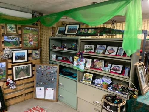 A cozy display of artwork and crafts on shelves, featuring framed pictures, handmade items, and decorative elements.