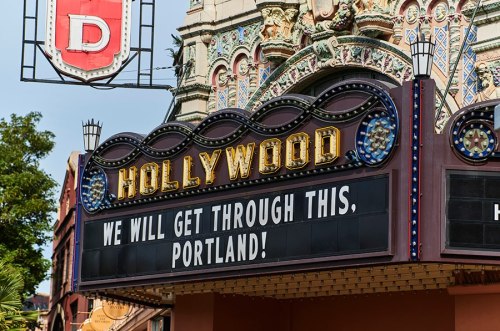 Sign outside the Hollywood Theatre in Portland reads, "WE WILL GET THROUGH THIS, PORTLAND!" with decorative architecture above.