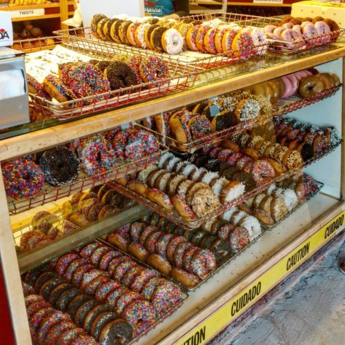 A display case filled with a variety of colorful donuts, including sprinkles, chocolate, and glazed options.