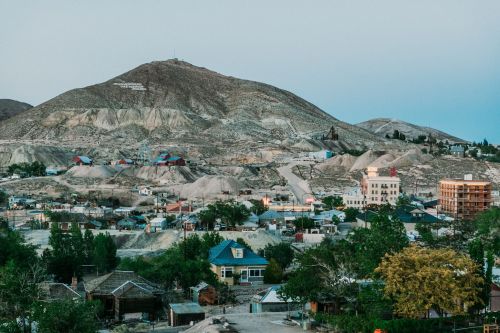 A view of a small town nestled in a valley, surrounded by hills and mountains, with houses and sparse vegetation.