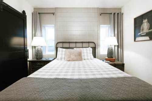 Cozy bedroom featuring a metal bed frame, plaid bedding, two lamps, and a decorative owl print on the wall.