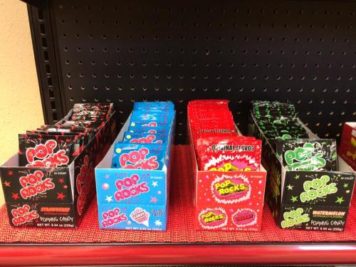 Colorful boxes of Pop Rocks candy in various flavors, arranged neatly on a display shelf.