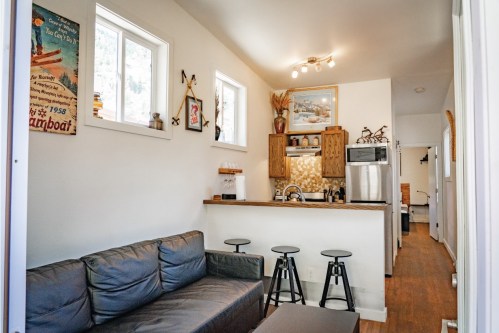 Cozy interior of a small kitchen and living area with a sofa, bar stools, and decorative wall art.