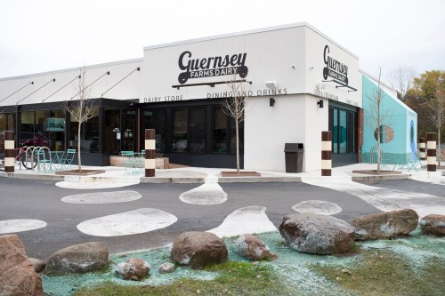 Exterior of Guernsey Farms Dairy store, featuring modern architecture, outdoor seating, and a colorful mural.