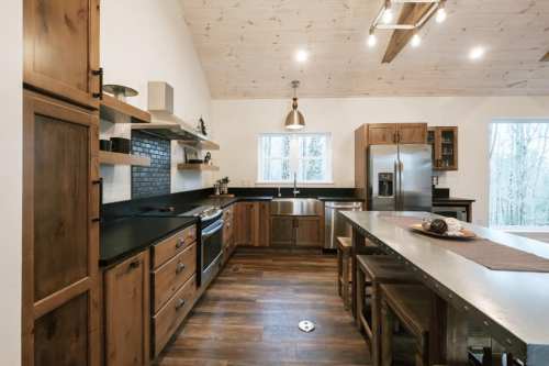 Modern kitchen with wooden cabinets, stainless steel appliances, and a large island, featuring natural light and a rustic design.