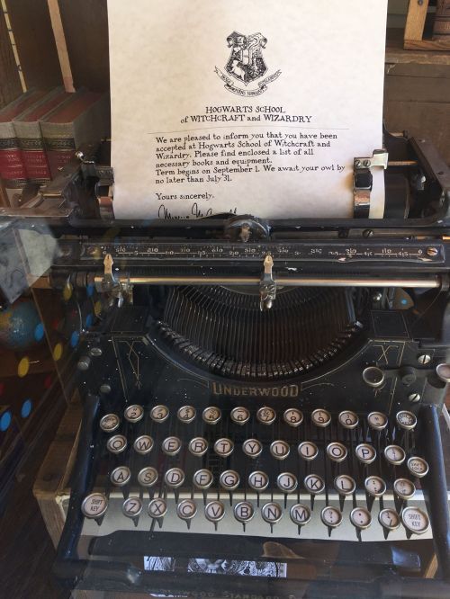An old typewriter with a letter from Hogwarts School of Witchcraft and Wizardry on top, announcing owl delivery details.