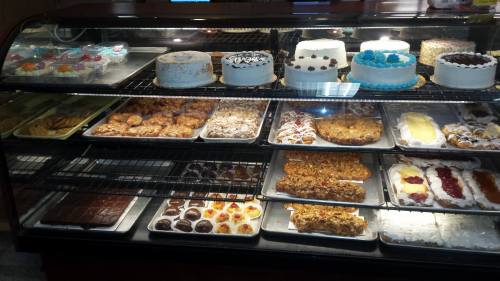 A display case filled with various cakes, pastries, and desserts, including cookies, brownies, and decorated cakes.