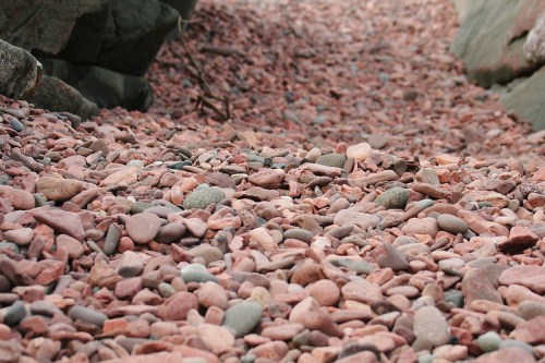 A close-up view of a pathway covered in smooth, colorful pebbles and stones, surrounded by rocky terrain.
