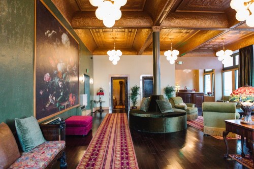 Elegant lounge with ornate ceiling, plush seating, floral artwork, and warm lighting, creating a cozy atmosphere.