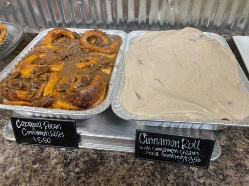 Two trays of cinnamon rolls: one with caramel pecan and the other with cinnamon cream cheese frosting, both priced at $3.50.