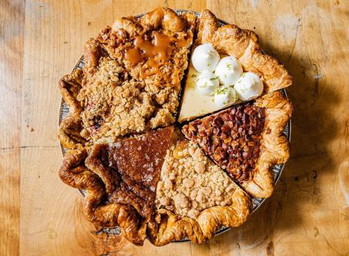 A pie divided into six sections, featuring various fillings and toppings, on a wooden surface.