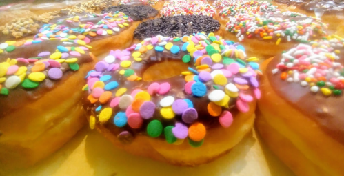 A close-up of colorful donuts topped with chocolate icing and vibrant sprinkles, arranged on a tray.