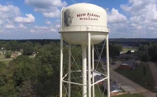 Aerial view of a water tower in New Albany, Mississippi, featuring a large portrait and the town's name.