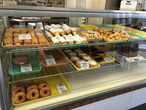 A display case filled with various pastries and donuts, including glazed, frosted, and cream-filled options.