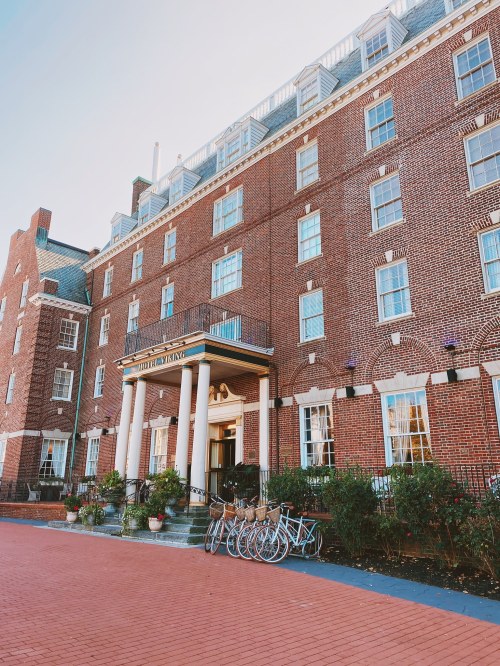 Historic brick building with a grand entrance, featuring columns and bicycles parked outside on a sunny day.