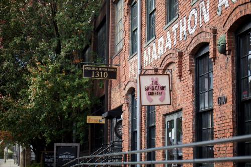 Brick building exterior featuring signs for Marathon Motor Works and The Bang Candy Company, with trees in the background.