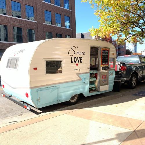 A vintage-style food trailer named "S'more Love" parked on a city street, with colorful signage and a cozy vibe.