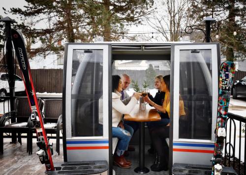 A group of four friends toasting drinks inside a cozy ski gondola, surrounded by snow and ski equipment.