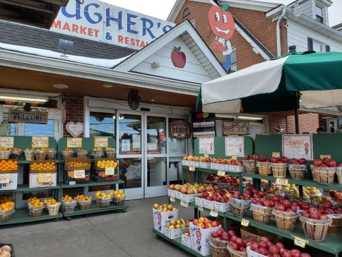 Exterior of a market with colorful fruit displays and a cheerful sign featuring a cartoon character.