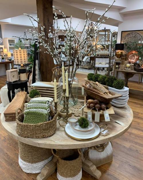 A beautifully arranged display of home decor items, including candles, plates, and decorative plants on a round table.