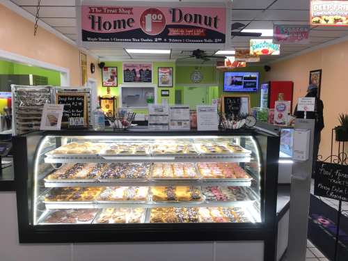 A display case filled with various donuts in a colorful donut shop, with menu signs and a cozy interior.