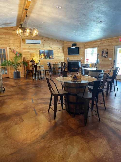 Cozy interior of a wooden room with tables, chairs, and a TV, featuring warm lighting and a rustic atmosphere.