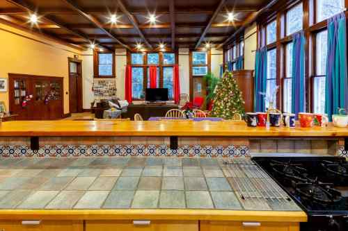 A spacious kitchen with a tiled island, overlooking a cozy living area decorated for the holidays with a Christmas tree.