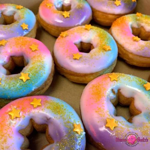 Colorful donuts with a gradient of purple, pink, and blue icing, topped with stars and glitter.