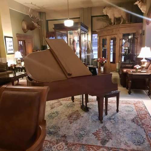 A grand piano in a cozy, elegantly furnished room with rustic decor and soft lighting.