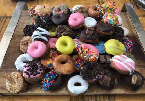 A colorful assortment of donuts with various toppings, arranged on a wooden platter.