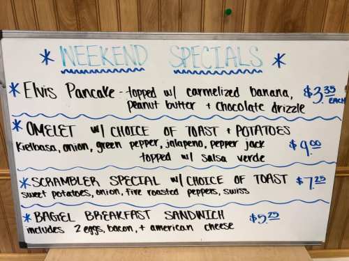 Whiteboard listing weekend specials: Elvis Pancake, Omelet, Scrambler Special, Bagel Breakfast Sandwich with prices.
