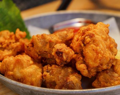 A close-up of crispy fried chicken pieces served in a bowl with a side of dipping sauce.
