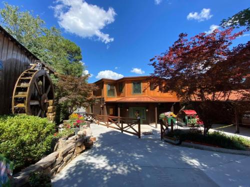 A rustic building with a wooden exterior, surrounded by greenery and a blue sky with fluffy clouds.