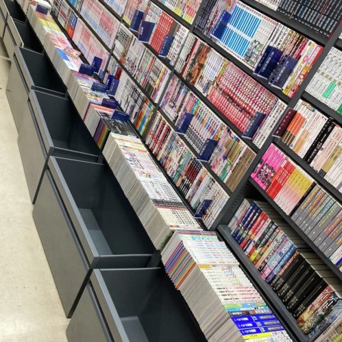 A bookstore aisle filled with colorful manga volumes neatly arranged on shelves and in bins.