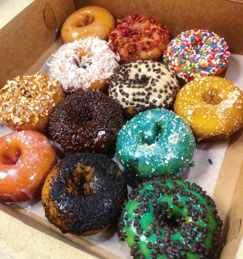 A box of twelve assorted donuts with various toppings, including sprinkles, chocolate, and coconut.