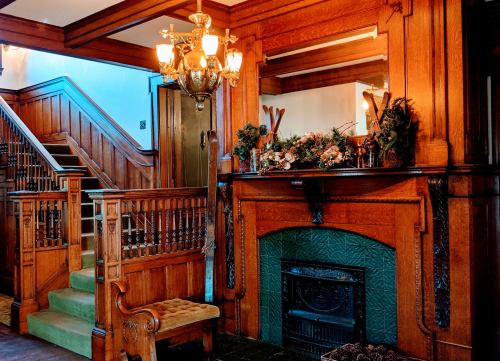 A vintage interior featuring a wooden staircase, ornate chandelier, and a decorated fireplace with floral accents.