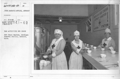 Three women in Red Cross uniforms serve food at a canteen during wartime, with bowls and a large container in the background.
