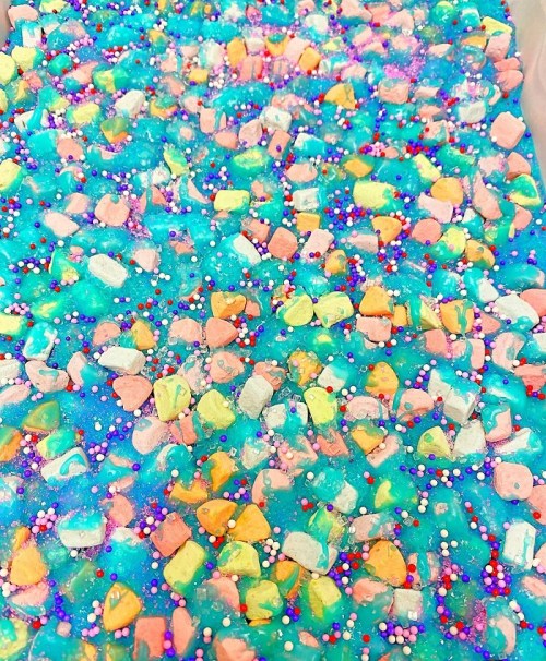 Colorful, textured surface with blue background, scattered pastel stones, and vibrant sprinkles.