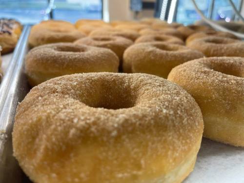 A close-up of freshly baked, sugar-coated donuts arranged on a tray.