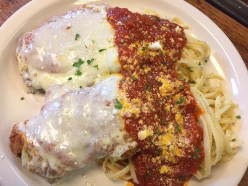 A plate of chicken parmesan topped with melted cheese and marinara sauce, served with a side of spaghetti.