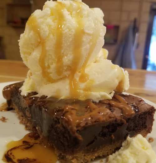 A rich brownie topped with a scoop of vanilla ice cream and drizzled with caramel sauce.