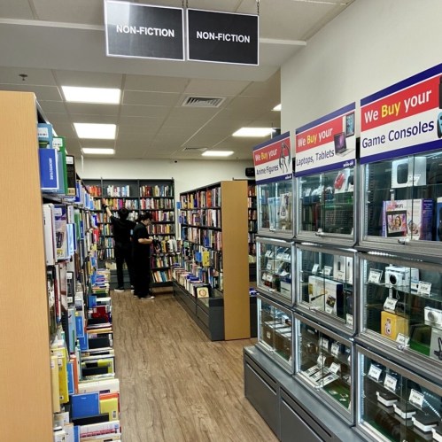 A bookstore aisle labeled "Non-Fiction" with shelves of books and display cases for electronics.