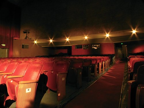 Empty theater with red seats and dim lighting, showcasing a quiet, nostalgic atmosphere.