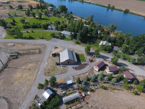 Aerial view of a rural area with houses, greenery, and a river nearby, showcasing a peaceful landscape.