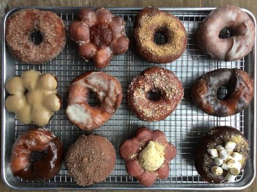 A tray of assorted donuts in various shapes and flavors, including glazed, chocolate, and sprinkled varieties.
