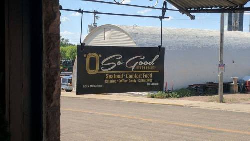 Sign for "O' So Good Restaurant" featuring seafood and comfort food, with details on catering and collectibles.