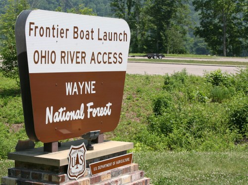 Sign for Frontier Boat Launch, Ohio River Access, located in Wayne National Forest, with greenery in the background.