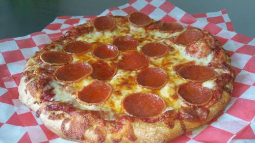 A freshly baked pepperoni pizza on a red and white checkered paper, featuring melted cheese and crispy crust.